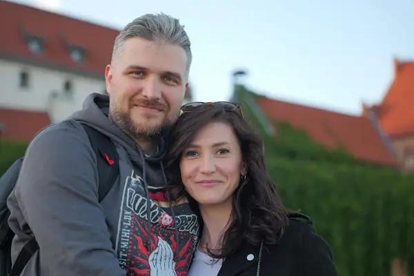 Ewa Zajączkowska-Hernik i jej mąż, uśmiechnięci na tle zabytkowych budynków.