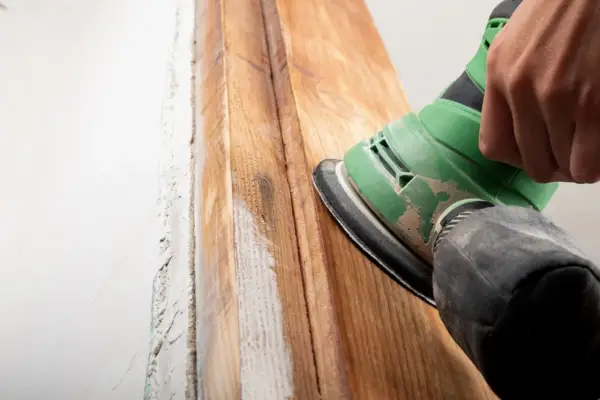 Lijando madera para quitar barniz viejo. El proceso de como quitar barniz de la madera se ve en acción con una lijadora.