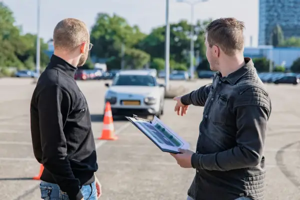Instruktor omawia z kursantem plan trasy, świętując jego pozytywny wynik egzaminu teoretycznego.