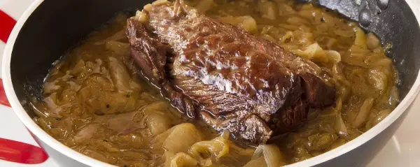 Une succulente buche d'onglet mijote dans une sauce aux oignons caramélisés, prête à être dégustée.