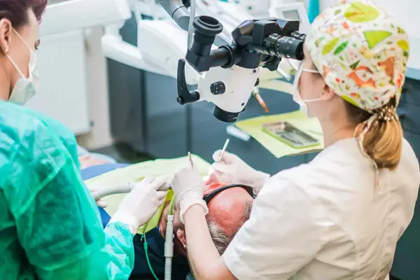 Stomatolog pod mikroskopem aplikuje lekarstwo w zębie pacjenta.