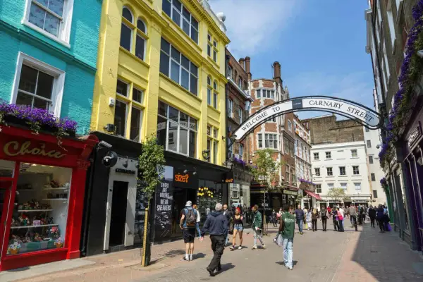Kolorowe fasady sklepów i łuk z napisem "Welcome to Carnaby Street" zapraszają do tętniącej życiem ulicy pełnej ludzi.