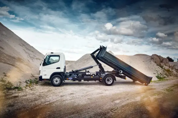 Biały Mitsubishi Canter z podniesioną skrzynią ładunkową na tle żwirowych hałd.