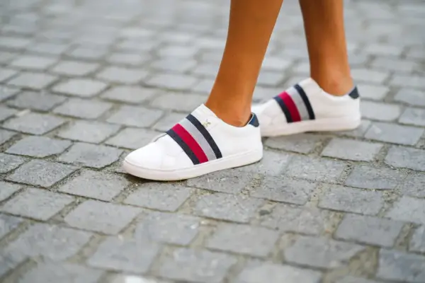 Białe trampki z kolorowymi paskami, rozmiar us 7, na brukowanej ścieżce.