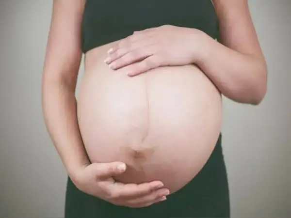 Kobieta w ciąży delikatnie głaszcze brzuch, zastanawiając się, jak pobudzić ruchy dziecka w brzuchu.