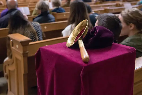 Gabe beim Gottesdienst: Eine Glocke auf einem mit Samt bezogenen Tisch, während Gläubige in den Kirchenbänken sitzen.