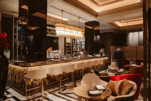 Elegante Bar mit goldenen Akzenten, weißen Barhockern und stilvollen Sitzbereichen. Ein Ort, der zu den besten Restaurants in Berlin passt.