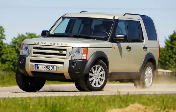 Złoty Land Rover Discovery 3 w ruchu, unoszący kurz. Temat: land rover discovery 3 awarie i problemy.