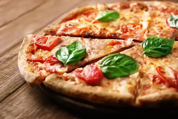 Klasyczna pizza Margherita, jak z Pizza Hut, z pomidorami i bazylią na drewnianym blacie.