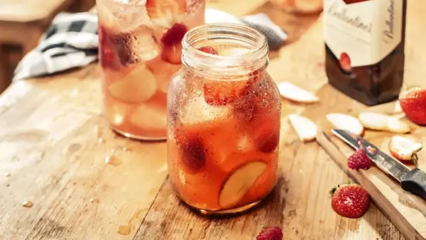 Orzeźwiający, kobiecy drink z whisky, pełen truskawek i jabłek, na drewnianym blacie.