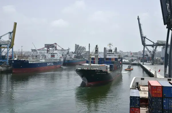 Navi da carico e gru nel porto di Casablanca. Un rimorchiatore assiste una nave portacontainer.