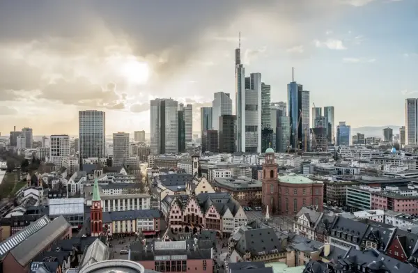 Widok na nowoczesne i zabytkowe frankfurt nad menem dzielnice, z drapaczami chmur i kościołami pod zachodzącym słońcem.