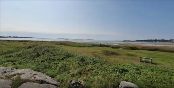 En bänk vid Rågelunds camping bjuder in till en stunds avkoppling med utsikt över vatten och grönska.