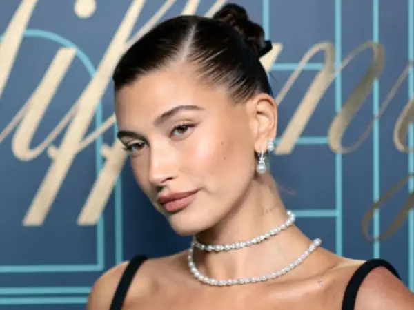 Elegancka kobieta z gładkim kokiem, w perłowej biżuterii, prezentuje klasyczny styl.