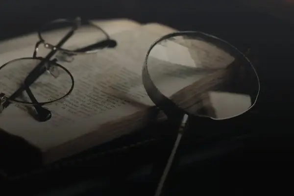 Brille und Lupe über einem alten Buch, bereit für eine tiefgehende Gedichtanalyse.
