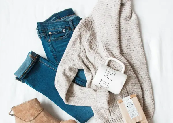 Ensemble pour s'habiller en hiver : jean, pull torsadé, bottines beiges, tasse et sachet de thé.
