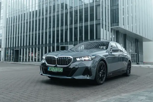 Eleganckie, szare BMW i5 z czarnymi felgami stoi przed nowoczesnym budynkiem biurowym.