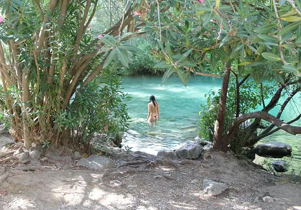 Una mujer se baña en la cueva del gato, un oasis de aguas cristalinas rodeado de vegetación exuberante.