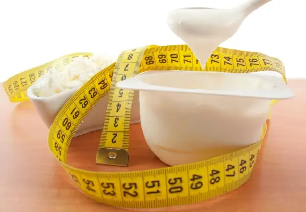 Biały jogurt i twaróg owinięte miarką. Czy od białka się tyje? Zdrowa dieta to klucz do sukcesu.