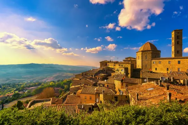 Un borgo toscano al tramonto, con tetti in cotto e un campanile svettante. Curiosità sulla Toscana: questo paesaggio evoca storie antiche.