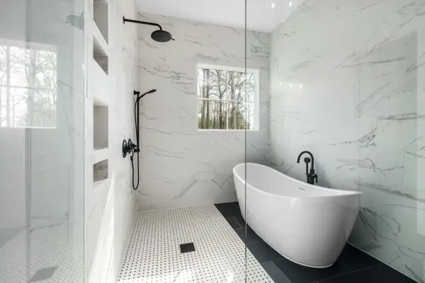 Salle de bain moderne avec baignoire îlot et douche vitrée, murs en porcelaine ou céramique effet marbre.