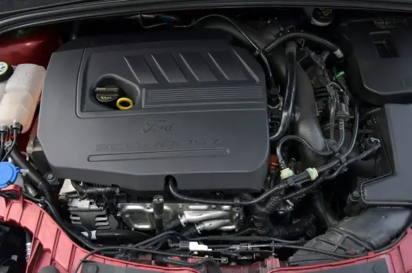 Silniki Ford Focus MK3 EcoBoost. Widok komory silnika z widocznym czarnym plastikowym elementem z napisem "Ford EcoBoost".