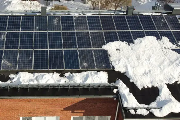 Snö täcker delar av solpanelerna på ett tak. Snart är det dags att skotta solpaneler för att fånga solens energi igen.