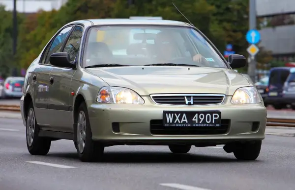 Złoty sedan Honda Civic z widocznym numerem rejestracyjnym WXA 490P. Brak tablicy rejestracyjnej z przodu.