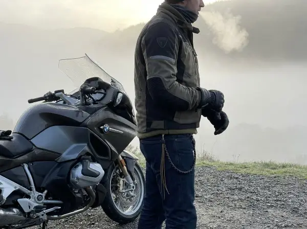 Motociclista con giacca tecnica e jeans, pronto per un'avventura. Ecco come vestirsi per andare in moto in ogni condizione.