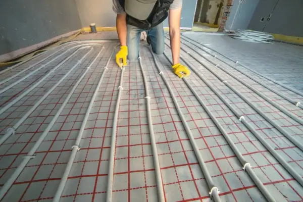 Instalator układa rury do ogrzewania podłogowego. Dokładna ilość metrów rury na m2 podłogówki zależy od projektu.