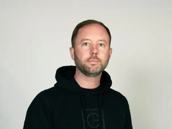 Daniel Holmgren, en man med blå ögon och skägg, bär en svart huvtröja.