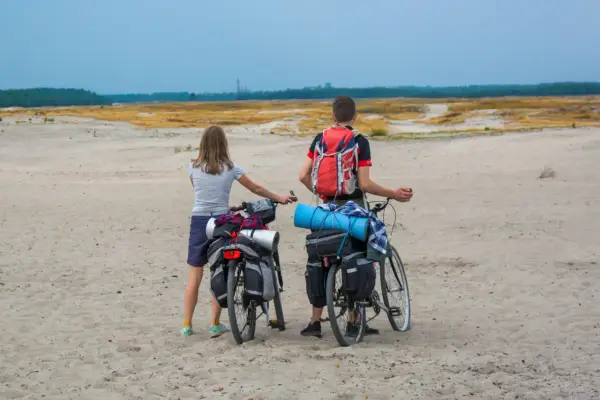Para rowerzystów z sakwami na rowerach na piaszczystej trasie rowerowej Pustynia Błędowska.