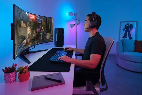 Un joueur concentré sur un écran d'ordinateur incurvé, profitant d'une immersion totale dans son jeu. La taille de l'écran offre une expérience visuelle captivante.