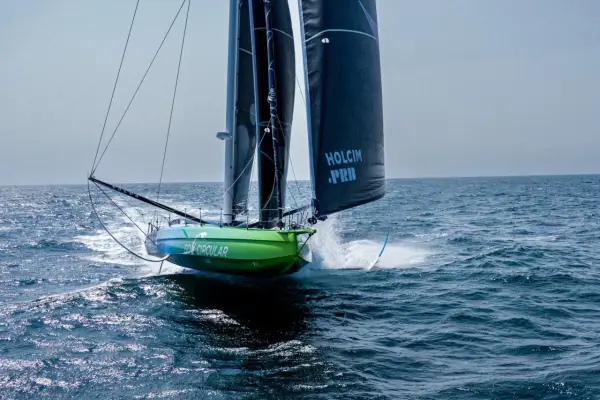 Voilier vert et bleu "Go Circular" naviguant à pleine vitesse, voiles noires marquées "Holcim PRB". Un design de Guillaume Verdier.