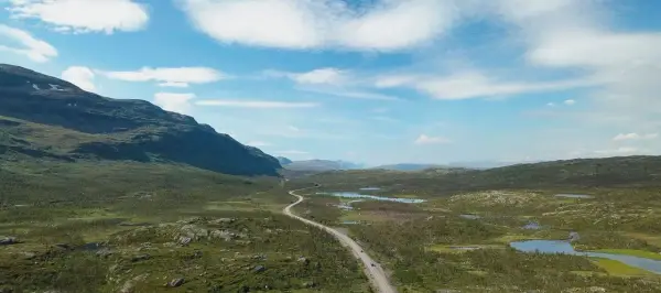 Väg slingrar sig genom ett vidsträckt landskap med berg och sjöar. Perfekt för camping i Norrbotten.