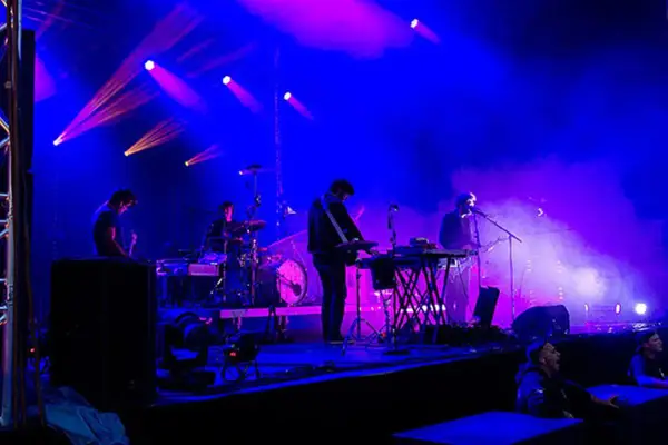 Un groupe allemand des années 2010 joue sur scène sous des lumières bleues et violettes.