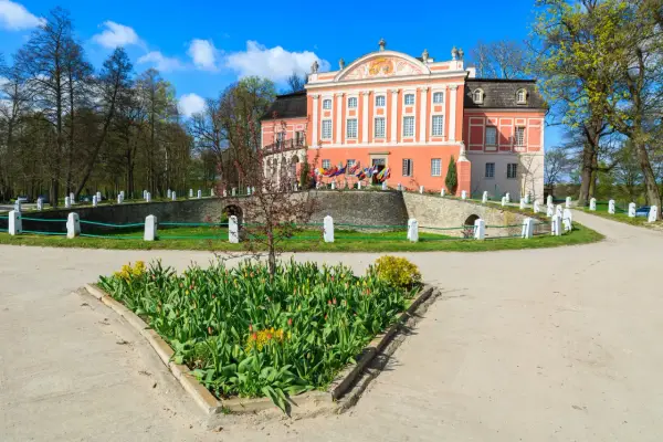 Kurozwęki atrakcje: barokowy pałac otoczony parkiem, z kwitnącymi tulipanami przed wejściem.