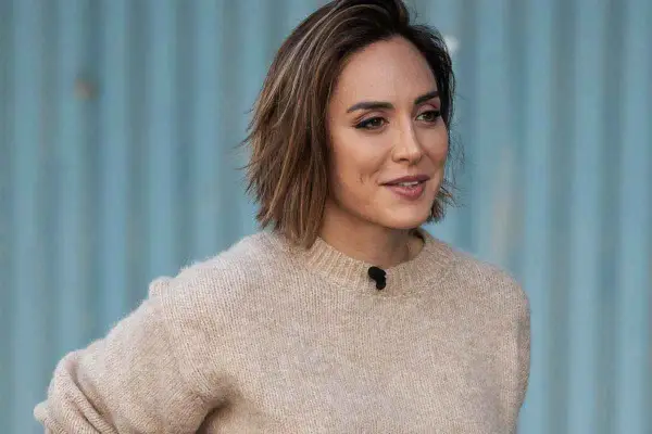 Mujer con un suéter beige y modernos cortes de pelo bob, con un fondo azul.