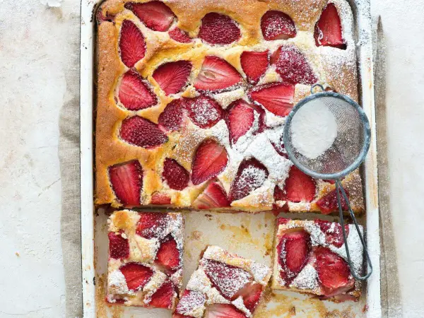 Le gâteau aux fraises de maman, doré et garni de fruits rouges, est saupoudré de sucre glace. Un délice !