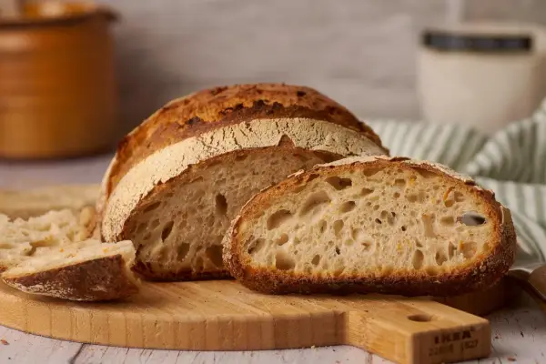 Ein frisch gebackenes reines Emmerbrot, aufgeschnitten auf einem Holzbrett. Die Krume ist luftig und goldbraun.