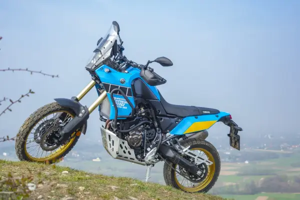 Niebiesko-żółty motocykl Yamaha Tenere 700 Rally gotowy na przygodę na wzgórzu.