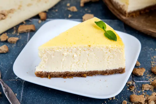 Ein cremiges Stück New York Cheesecake mit einem Keksboden, garniert mit Minze.