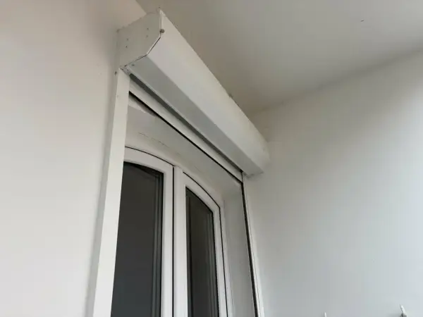 Un imposte blanc est installé au-dessus d'une porte-fenêtre blanche.