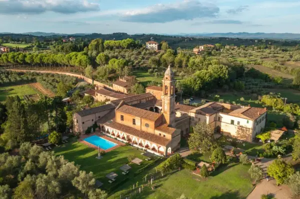 Un'antica dimora con campanile e una splendida piscina toscana, immersa nel verde delle colline.