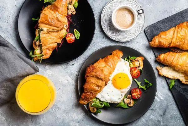 Typowe amerykańskie śniadanie: croissant z jajkiem sadzonym, pomidorkami i grzybami, do tego kawa i sok.