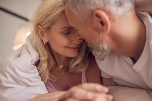 Couple âgé sous une couverture, évoquant la tendresse malgré la baisse de libido chez l'homme de 50 ans.