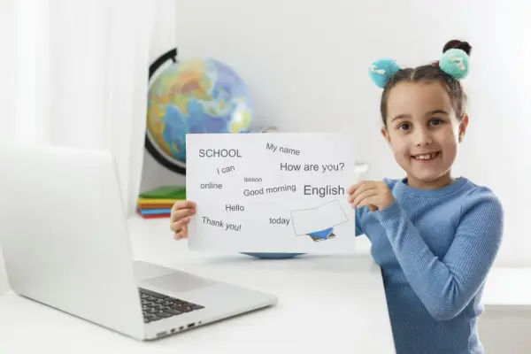 Uśmiechnięta 7 latek pokazuje kartkę z angielskimi słówkami: "English", "Hello", "Thank you!".