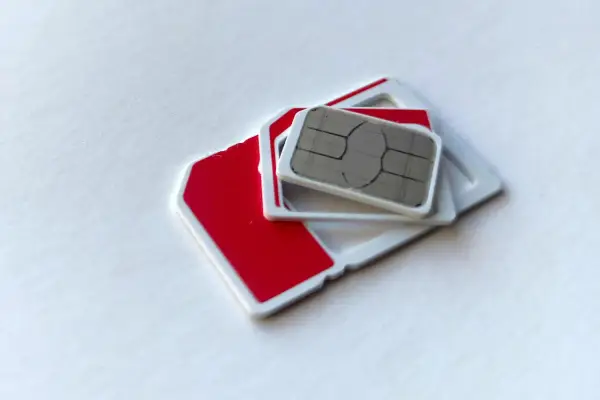 Dwie karty SIM, jedna czerwona, druga z metalowym chipem, leżą na białym tle. Szukasz najtańszej karty SIM?