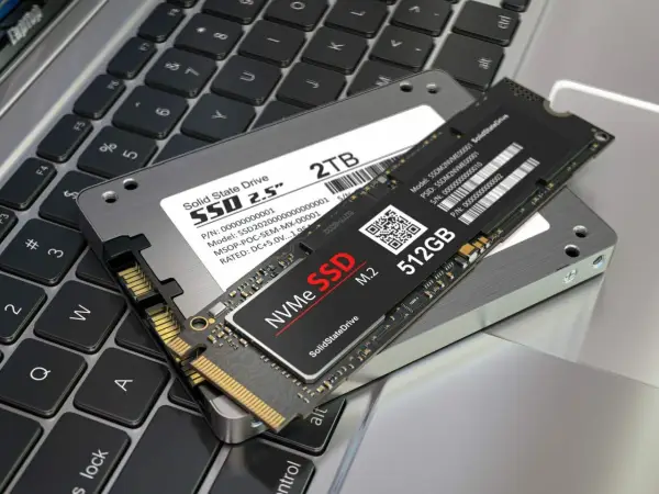 Dwa dyski SSD: 2.5" 2TB i M.2 NVMe 512GB, leżące na klawiaturze laptopa. Jaki dysk SSD do laptopa wybrać?