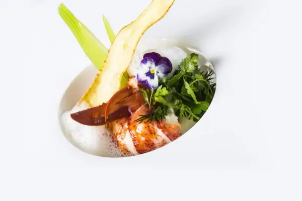 Homard poêlé, écume légère, chips de légume et fleur, une spécialité jurassienne raffinée.